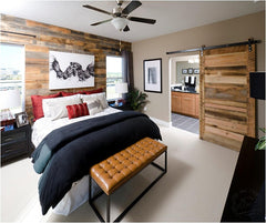This bedroom gains much depth and character from reclaimed wall paneling and a sliding barn door on the master bathroom.